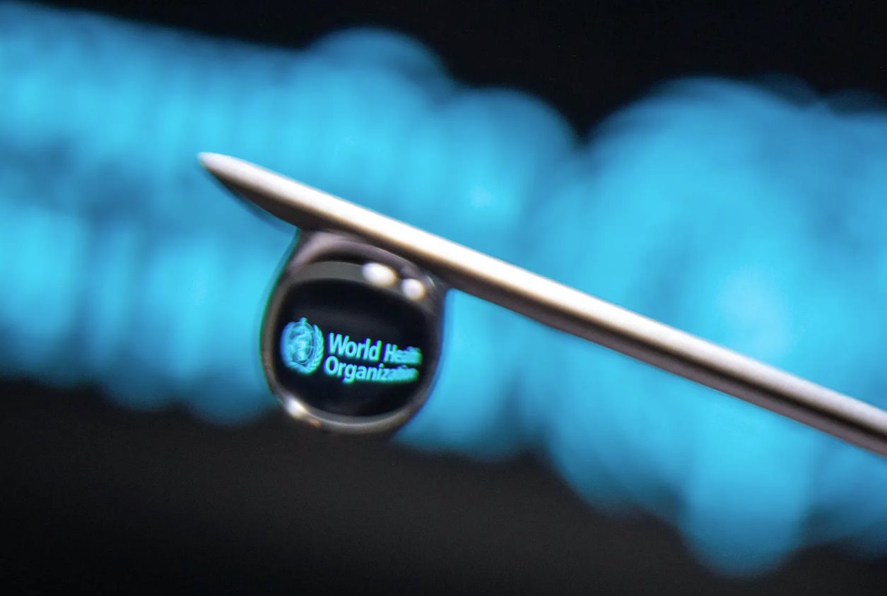在這張拍攝于2021年3月16日的插圖照片中，世界衛(wèi)生組織的徽標(biāo)反映在注射器針頭上的一滴水滴中