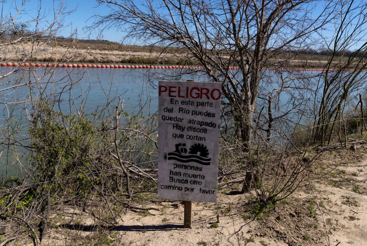 2024年2月25日，墨西哥科阿韋拉州彼德拉斯內(nèi)格拉斯，一塊標(biāo)志警告移民試圖通過(guò)格蘭德河上的漂浮屏障進(jìn)入美國(guó)將面臨極大危險(xiǎn)。