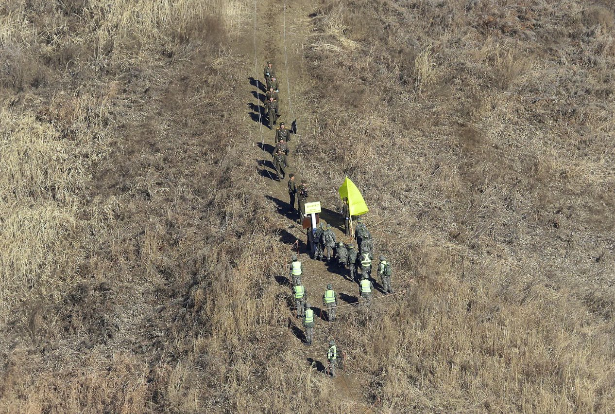 2018年12月12日，朝鮮軍隊士兵（上）越過非軍事區(qū)(DMZ)內(nèi)的軍事分界線，檢查已拆除的韓國哨所，韓國軍隊士兵則在鐵原的朝韓邊界中部地區(qū)觀看。