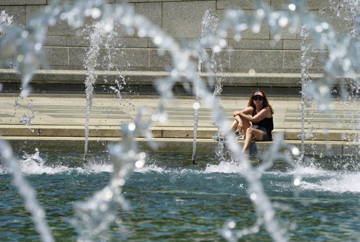 2024年4月29日，美國(guó)華盛頓，在可能創(chuàng)紀(jì)錄的高溫日，一名戴著星條旗遮陽(yáng)帽的女士將腳浸入二戰(zhàn)紀(jì)念館的涼爽噴泉中。